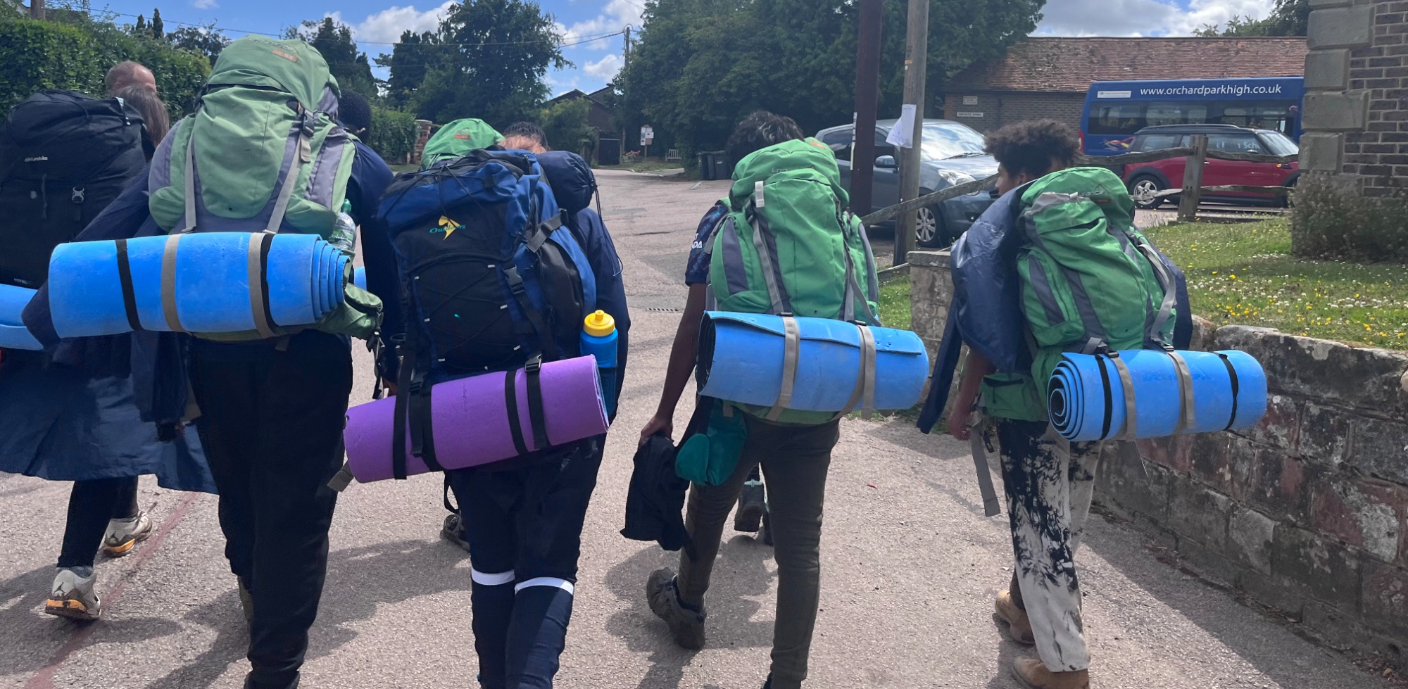 Students walking with all their camping kit and rucksacks
