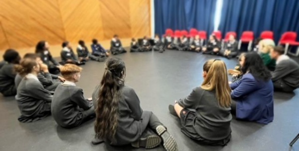 Circle of students sitting on floor of drama studio