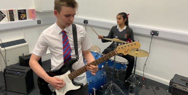 Student playing drums and students playing guitar