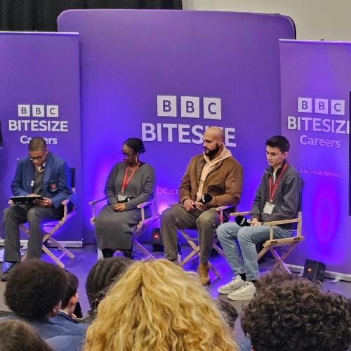 Students sitting with presenters in front of a BBC Bitesize big screen.